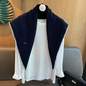 Détail d'un châle triangle en laine bleu marine avec dentelle blanche et maille douce