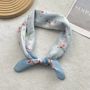 Detail of light blue floral cotton linen scarf with red blossoms and navy border