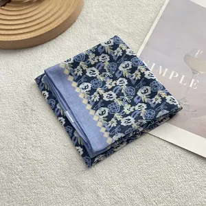 Detail of blue floral cotton linen scarf with checkered border on white fleece