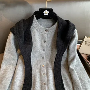 Detail view of grey knit cardigan buttons and matching black knitted shawl scarf