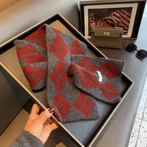Detail of a red and grey argyle wool scarf folded in a tray with stylish accessories