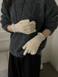 Detail of off-white knit gloves with lace cut-outs and ruffled edges on sleeves