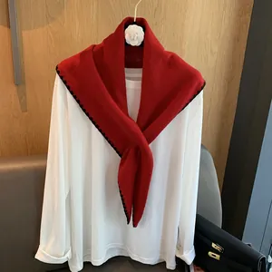 Détail d'un châle en laine rouge avec broderie festonnée noire sur un cintre élégant