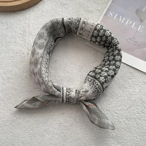 Dettaglio di un foulard in seta vintage con motivi patchwork annodato su sfondo bianco