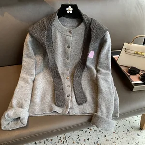 Detail of grey knitted cardigan and shawl set showing ribbed cuffs and button closure