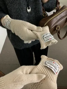 Detail of cream knit glove with vintage flower label and intricate crochet texture