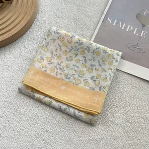 Close-up of floral cotton linen scarf with yellow borders and star patterns on grey surface