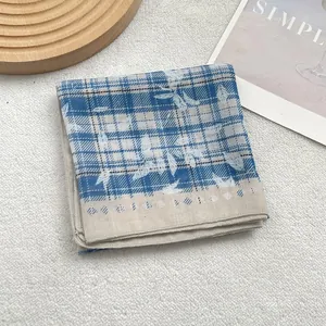 Plaid blue and white cotton scarf with leaf prints on white textured background