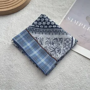 Dettaglio di un foulard in cotone e lino bianco e blu con motivi floreali su vassoio in legno