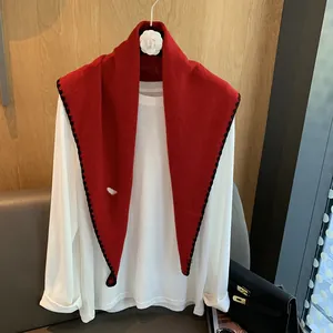 Détail du châle en tricot de laine rouge avec une bordure festonnée noire décorative