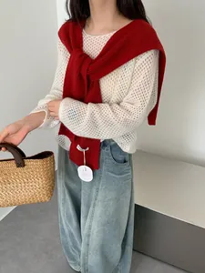 Detail van de rode geribde gebreide trui over een witte mesh gebreide top voor dames