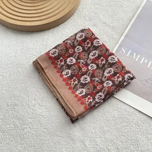 Detail view of a vintage floral linen-silk scarf with wave edges on a plush white background