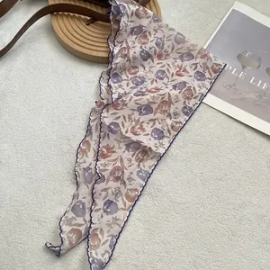 Close-up of floral linen triangle scarf with purple tulip print and wavy blue hem stitch