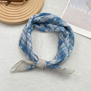 Blue and beige checkered square scarf styled as a bow tie on white velvet background