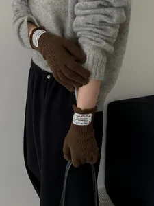 Close-up of dark brown hollow knit wool gloves featuring a vintage white woven label