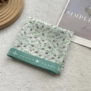 Detailed macro view of a floral cotton linen scarf with soft mint green dotted borders