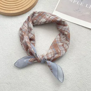 Detail of checkered silk scarf showing stitching edges and soft fabric texture on plush