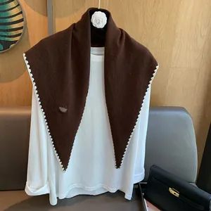 Détail de la maille d'un châle triangulaire en laine marron avec bordure festonnée