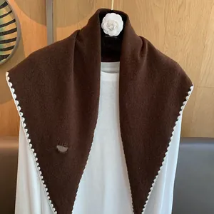 Détail d'un châle en laine marron foncé avec bordure festonnée blanche et maille fine