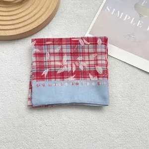Detailed view of red and white checkered silk scarf with white floral leaf patterns
