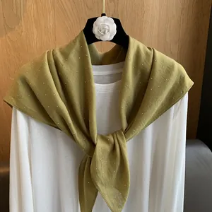 Écharpe en coton et lin vert olive avec strass argentés sur fond de bois