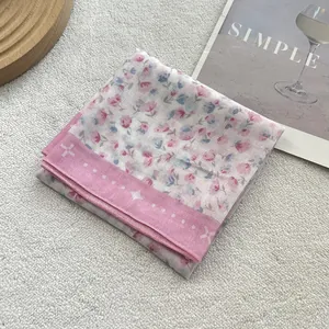 Close-up of pink floral cotton linen scarf with polka dot borders on a textured fabric