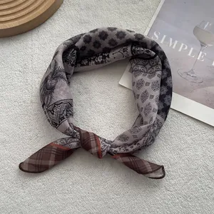 Dettaglio di una sciarpa vintage in lino con motivi paisley e geometrici su fondo ruvido