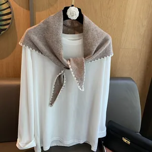 Détail du châle en tricot de laine marron café avec bordure en dentelle sur un t-shirt