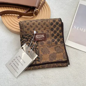 Brown floral print cotton scarf with vintage leaf pattern and brand label on a wooden tray