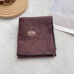 Detail of vintage reddish-brown floral cotton scarf with REVIVAL brand label and black edging