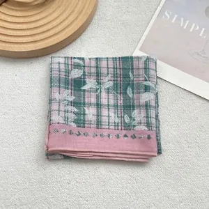 Detail of pink and green plaid cotton scarf with white leaf print and stitched edges