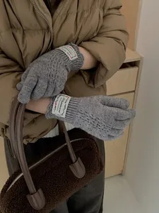 Detail of grey hollow-knit gloves with white label and textured wool blend finish