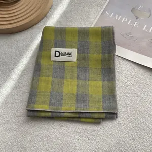 Detail of the blue and yellow plaid cotton scarf texture with fine stitching and brand label