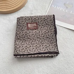 Detailed close-up of a vintage cotton scarf with floral print and a leather brand label