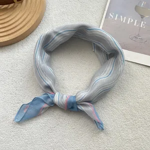 Close-up of blue and white striped cotton scarf tied in a knot on a white textured rug