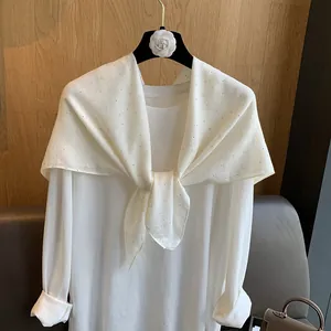 Détail de l'écharpe en coton blanc ornée de strass brillants et de tissu léger