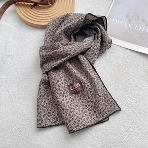 Detailed close-up of ditsy floral print cotton scarf with brand tag on soft fabric