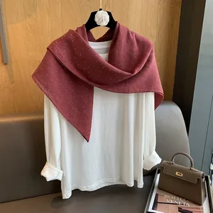 Détail d'une écharpe en lin bordeaux à pois blancs sur un haut blanc minimaliste