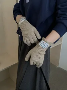 Close-up of oatmeal lace-knit fingerless gloves with vintage label and floral pattern