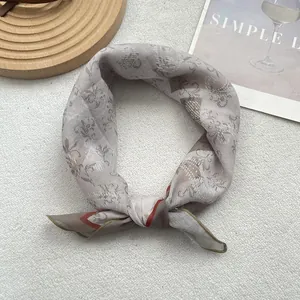 Macro shot of retro floral patterned scarf with orange trim on a white textured background