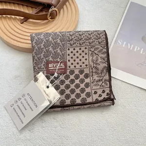Detail view of cotton scarf with vintage floral print and brand label on textured surface