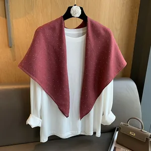 Détail d'un foulard triangle rouge foncé à pois en coton et lin drapé sur un haut blanc