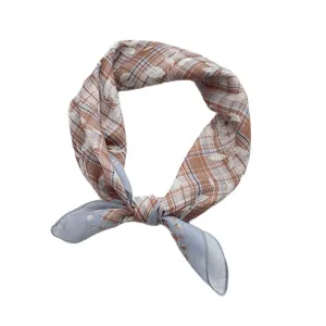 Vintage plaid silk scarf in brown and blue colors tied in a knot on white background