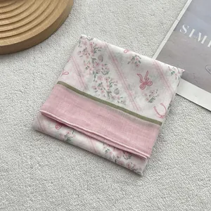 Foulard floral en coton plié avec fleurs roses et ruban vert sur fond de tissu crème