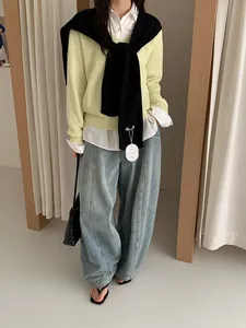 Chique gelaagde look met gele gebreide trui, wit shirt, zwarte sjaal en denim jeans
