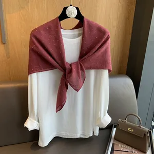 Détail d'un haut en coton blanc avec un châle à pois bordeaux sur un cintre en bois