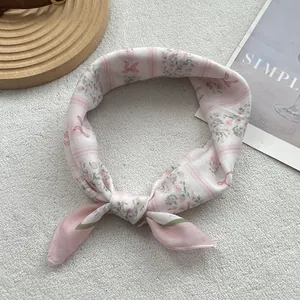 Détail du foulard en soie rose à fleurs avec nœud et texture à rayures fines