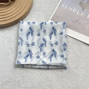 Macro view of light cotton-linen square scarf featuring blue floral patterns on white base