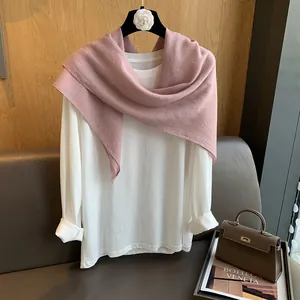 Détail d'une écharpe en coton et lin rose avec perles fines et détail de fleur de camélia