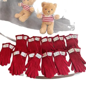 Red knit fingerless gloves with cable stitch pattern and decorative woven label